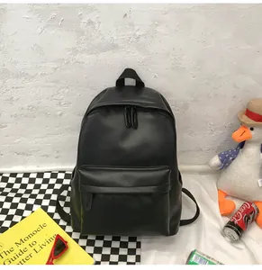 Detail view of the black PU leather backpack with a large front pocket and top handle