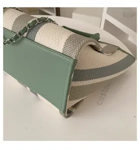Dettaglio della borsa tote in tela a righe con finiture in pelle verde menta e catena
