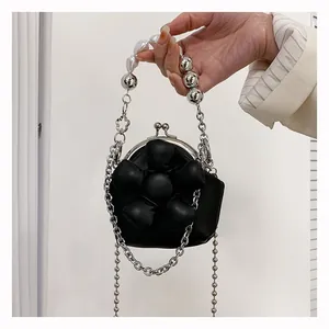 Detailed shot of a black mini crossbody bag featuring a large 3D flower and pearl handle
