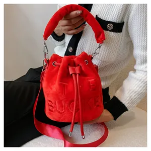 Detail of red plush bucket bag showing THE BUCKET embossed text and drawstring closure