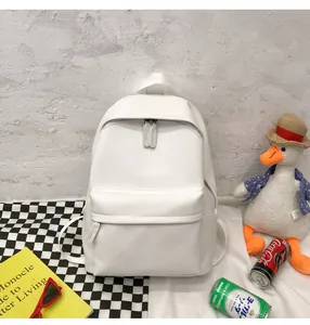 Minimalist white PU leather backpack with front zipper pocket on a checkered tablecloth