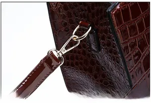 Close-up of brown crocodile pattern patent leather handbag with gold metal hardware