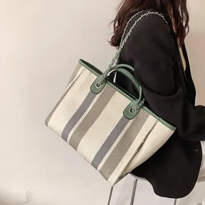Dettaglio della borsa tote in tela a righe con finiture in pelle verde e tracolla