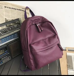 Close-up of purple litchi grain leather backpack with vintage radio and newspapers