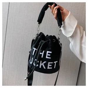Detail of plush black bucket bag featuring white THE BUCKET embroidery and drawstring closure