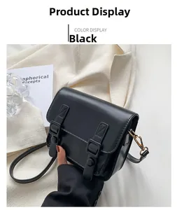 Detailopname van zwarte crossbodytas van kunstleer met metalen gespen en gouden haken