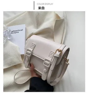 Detail van gebroken witte PU-leren crossbodytas met dubbele gespen en smalle riem