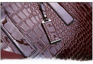 Detail of glossy brown crocodile embossed leather handbag with high-quality stitching
