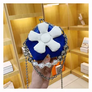 Detail of blue mini bag with 3D white flower and chunky pearl metal chain strap