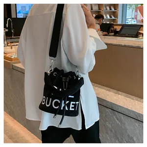 Detail of plush bucket bag with white BUCKET lettering and wide nylon strap