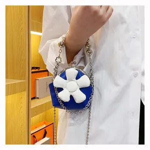 Detail of navy mini bucket bag featuring 3D white flower, silver bead handle and chain strap