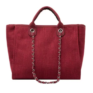 Primer plano del bolso tote de lona roja con textura tejida y cadena de plata