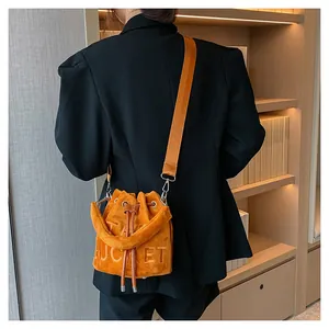 Detail of caramel suede bucket bag showing THE BUCKET embossing and drawstring closure