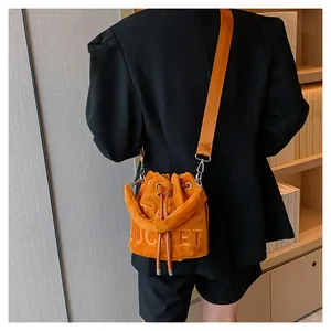 Detail showing plush orange bucket bag with embossed bucket letters and wide shoulder strap