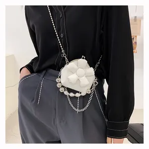Detail of white flower-shaped mini bag featuring silver chain and pearl pendant