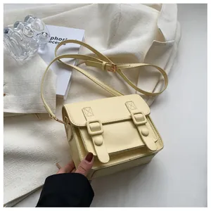 Detail van een crèmegeel rechthoekige crossbodytas met retro gespen in een lifestyle setting