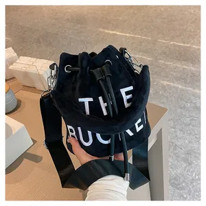 Detailed close-up of plush black bucket bag with white THE BUCKET embroidery detail