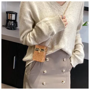 Vue détaillée du mini sac bandoulière doré en strass porté avec une tenue élégante