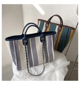 Dettaglio macro della borsa tote in tela a righe con rifiniture in pelle e catena