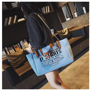 Detailansicht der hellblauen Segeltuchtasche mit braunen Lederriemen und Textdesign