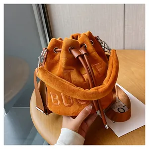 Detailed close-up of bright orange plush bucket bag with embroidered lettering and silver hook