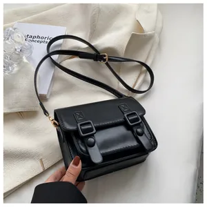 Detail van zwarte vintage crossbodytas met flap en decoratieve gouden gespen erop