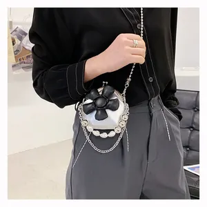 Detailed view of silver mini crossbody bag with black flower and pearl chain strap