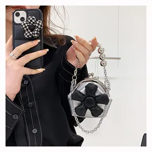 Macro view of metallic silver mini bag featuring a large 3D black flower and kiss-lock closure