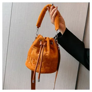 Detail of orange plush bucket bag featuring The Bucket embossed text and leather drawstring