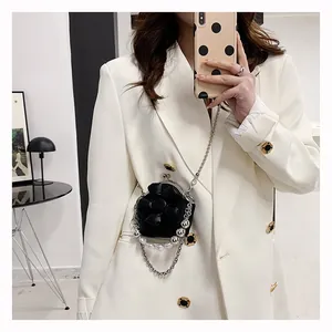Mini black crossbody bag with 3D floral accent and pearl chain on white blazer
