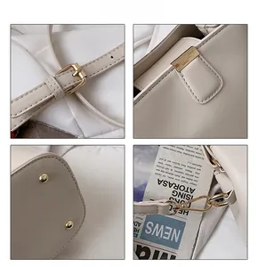 Detail view of cream bucket bag showing gold hardware, adjustable strap and bottom studs