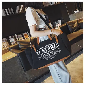 Detailansicht einer schwarzen Canvas-Einkaufstasche mit braunem Leder und Retro-Buchstaben