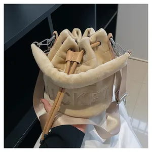 Detail of plush beige bucket bag with embossed BUCKET text and wide woven strap