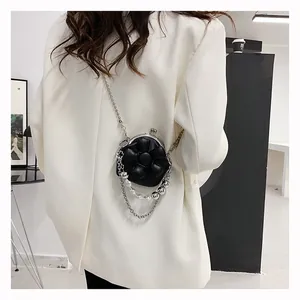 Detail of a mini floral crossbody bag with pearl accents and a silver chain strap