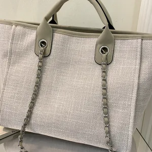 Detalle del bolso tote de lona con tela crema y adornos de cuero marrón y cadena