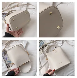 Detail view of cream bucket bag showing metal feet and adjustable leather strap
