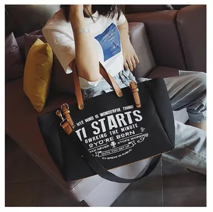 Detail einer schwarzen Canvas-Tasche mit weißem Retro-Text und braunen Kunstlederriemen