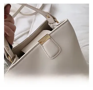 Detailed close-up of golden metal hardware and buckle on a beige leather bucket bag