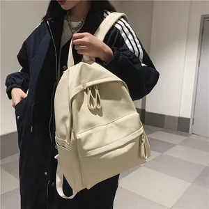 Minimalist beige pebble leather backpack with front pocket and woven straps for daily commuting