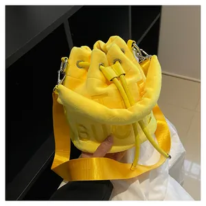 Detail of yellow plush bucket bag featuring 3D BUCKET lettering and drawstring closure