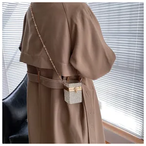 Détail d'un mini sac bandoulière scintillant en strass avec chaîne dorée sur un trench