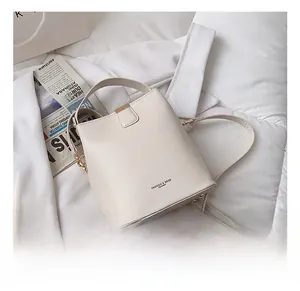 Detail of cream white bucket bag with gold studs and polished leather texture