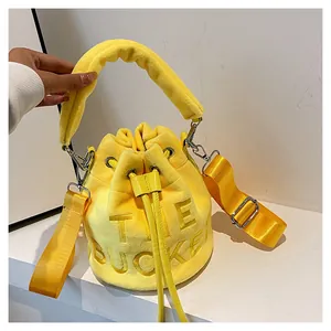 Detailed view of yellow plush bucket bag featuring embossed THE BUCKET lettering and straps