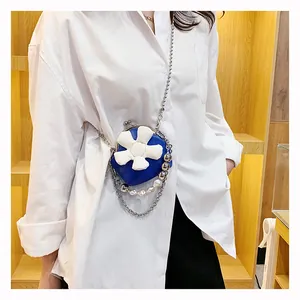 Detail view of mini blue crossbody bag with white flower and pearl chain strap