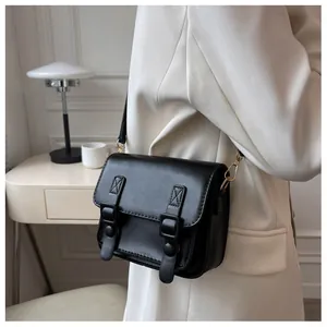 Detail van een chique zwarte leren kleine vierkante tas gestyled met een witte blazer