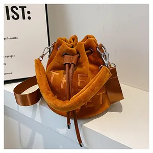 Detail of orange velvet bucket bag featuring letter embroidery and brown leather drawstring