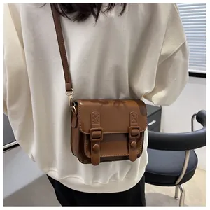 Detail van donkerbruine crossbodytas met vintage gespen en gouden metalen haken