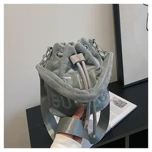 Close-up of grey plush bucket bag with The Bucket embroidery and metal chain strap