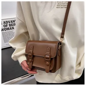 Detail van vintage bruine crossbody tas met dubbele gesp en fijne stiksels