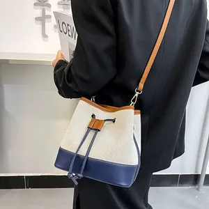 Minimalist canvas bucket bag with navy leather trim and drawstring closure for women